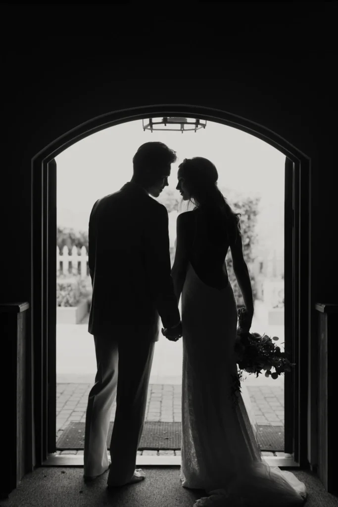 A bride and groom holding hands in front of an arch.